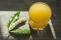 A spikelet of ripe wheat with green leaves and a glass of freshly squeezed orange juice in a glass glass on a wooden