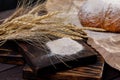 Spikelets and flour and craft bread closeup on a wooden board and burlap. The concept of healthy food and traditional bakery Royalty Free Stock Photo