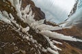 Spiky, icy stalagmites created from the roof of a mountain next to the Kvernufoss waterfall, seen from a vantage point as if it