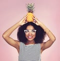 Spiky on the outside but sweet inside. Studio shot of a beautiful young woman posing with a pineapple on her head. Royalty Free Stock Photo