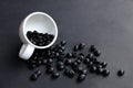 spilled black coffee beans from white cup on dark floor Royalty Free Stock Photo
