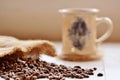 Spilled coffee beans from canvas sack and ceramic mug Royalty Free Stock Photo