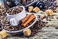 Spilled coffee beans in coffee cup on a very old wooden table with cane sugar. In the background an old coffee grinder. Royalty Free Stock Photo