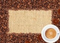 Spilled coffee beans frame over burlap textile and coffee cup Royalty Free Stock Photo