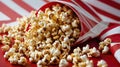 Popcorn Overflowing from a Striped Container on Red Surface - Movie Night Treat Royalty Free Stock Photo