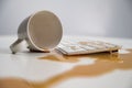 Spilled cup of black coffee on computer keyboard on white table. Royalty Free Stock Photo