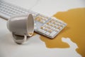 Spilled cup of black coffee on computer keyboard on white table. Royalty Free Stock Photo