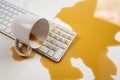Spilled cup of black coffee on computer keyboard on white table. Royalty Free Stock Photo
