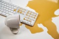 Spilled cup of black coffee on computer keyboard on white table.