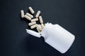 Spilled medical pills from white pill bottle on black background Royalty Free Stock Photo