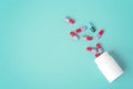 Spilled pills with white medicine bottle on green background Royalty Free Stock Photo