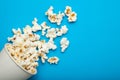 Spilled popcorn from a paper bucket or a cup on a blue background Royalty Free Stock Photo