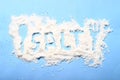 Spilled salt with text, spoon and fork shape at blue paper background Royalty Free Stock Photo