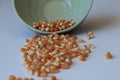 Corn seed in green ceramic bowl isolated on white background. Spilled seed pile.