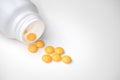 Spilled yellow pills from open prescription medication plastic white bottle gray background Royalty Free Stock Photo