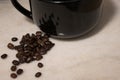 Spilt coffee beans beside a black mug Royalty Free Stock Photo