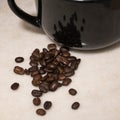 Spilt coffee beans beside a black mug Royalty Free Stock Photo