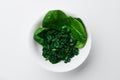 spinach (fresh and freeze spinach) blanch. on a white plate on a light background. Top view. Space for text. Mockup