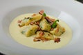 Spinach gnocchi with parmesan sauce topped with bacon