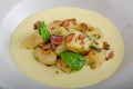Spinach gnocchi with parmesan sauce topped with bacon