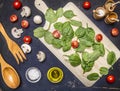 Spinach leaves and sliced mushrooms, laid out on a cutting board with herbs and cherry tomatoes on wooden rustic background top vi