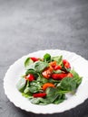 Spinach salad with pepper and tomatoes in white plate Royalty Free Stock Photo