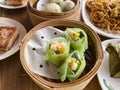 Spinach shrimp dumplings in a bamboo steamer on a table, with smoke from the hot basket of dim sum. Pan-fried carrot cake, crystal