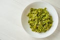 Spinach Tagliatelle . Vegan pasta with spinach, pesto sauce and pine nuts on a white plate. Top view.