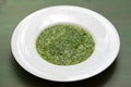 Spinach on white plate on green background