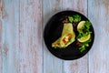 Spinach wrap with meat and vegetables on black plate with green salad Royalty Free Stock Photo