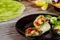 Spinach wrap with meat and vegetables on black plate with green salad Royalty Free Stock Photo