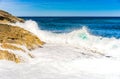 Rough sea waves with white water foam hitting against rocks at island coast Royalty Free Stock Photo