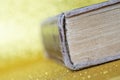 The spine of a thick old book lying on a yellow golden background. Library archive. History and memoirs. Literature and philology