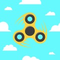 Spinner in a flat style. The yellow spinner turns against the blue sky. Flat, white clouds. A modern antistress toy for recreation