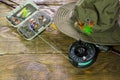 fly box with flies and a hat on a wooden table.