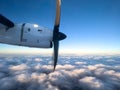 Spinning propeller of an airplane flying above the clouds in the blue sky