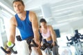 Spinning their way to toned bodies. A man and woman exercising in spinning class at the gym. Royalty Free Stock Photo