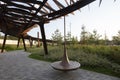 Spinning wooden bench and metal pergola. Walkway with grass lawn, bushes, plants, trees in background. Tyufeleva Roshcha city park Royalty Free Stock Photo