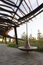 Spinning wooden bench and metal pergola. Walkway with grass lawn, bushes, plants, trees in background. Tyufeleva Roshcha city park Royalty Free Stock Photo