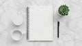 A spiral bound notebook with blank pages is centered on a marble surface Royalty Free Stock Photo
