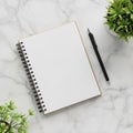A spiral-bound notebook with blank pages is placed on a white marble surface Royalty Free Stock Photo