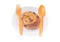 Spiral danish pastry with raisin on top on white plate with plastic spoon and fork served for breakfast isolated on white