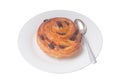 Spiral danish pastry or sweet bun with raisin on top on white plate with small teaspoon served for breakfast isolated on white