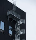 Spiral external emergency stairs by a black building.. Royalty Free Stock Photo