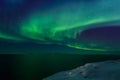 Spiral green Northern lights shining over the fjord with mountains in the background, Nuuk, Greenland