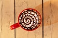 Spiral Latte art in Red Mug on Beige Wood Table