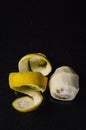 Spiral lemon peel and peeled whole lemon on a glittery black glass background with room for some text Royalty Free Stock Photo