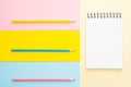 Spiral notebook with blank white sheet and colored pencils on multi-colored pape Royalty Free Stock Photo