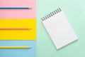 Spiral notebook with blank white sheet and colored pencils on multi-colored paper. Royalty Free Stock Photo