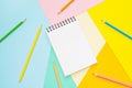 Spiral notebook with blank white sheet and colored pencils on multi-colored paper Royalty Free Stock Photo